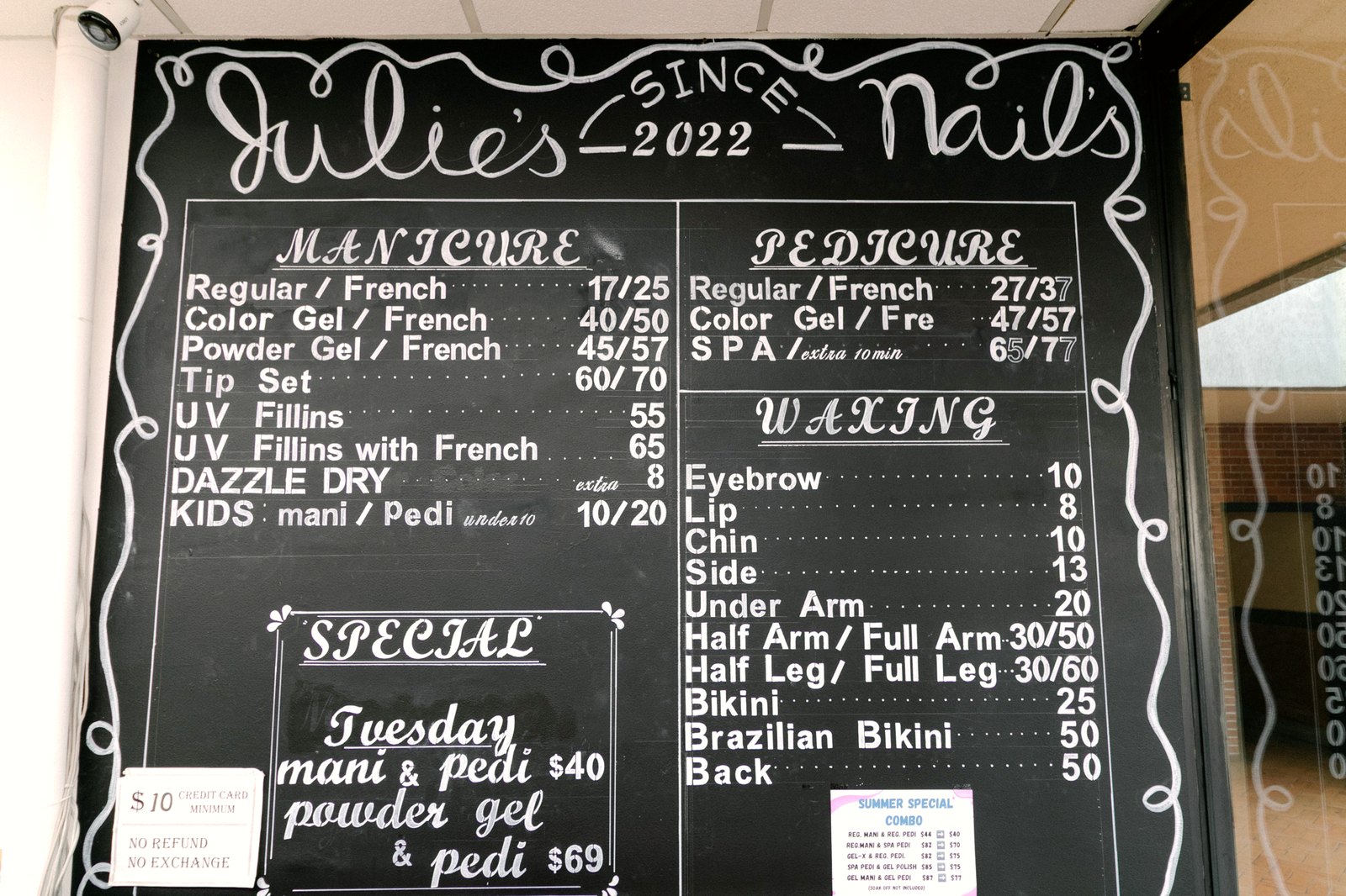 Hand-lettered chalkboard menu at Julie's Nails showing manicure, pedicure and waxing prices
